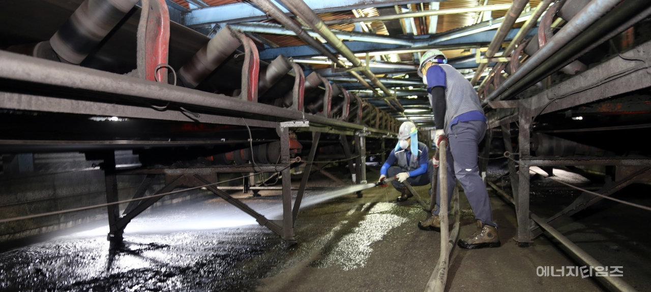 한전산업개발 직원들이 석탄발전소 내 발전연료인 유연탄을 이송하는 컨베이어벨트 아래 떨어져 있는 낙탄을 물청소하고 있다.