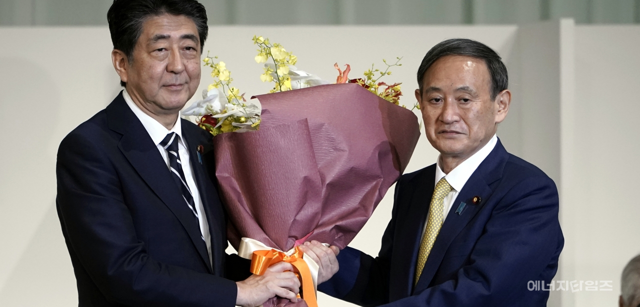 아베 일본 총리가 14일 도쿄의 한 호텔에서 열린 자민당 총재 선거에서 총재로 선출된 스가 요시히데 관방장관에게 꽃다발을 건네며 축하하고 있다. 스가 관방장관은 이날 열린 총재 선거에서 신임 총재로 선출됐다. / 사진=뉴시스